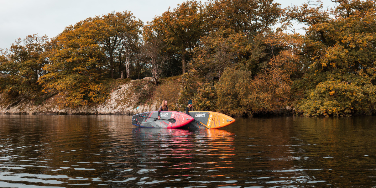two women holding paddleboards in lake, about to get ready to paddle