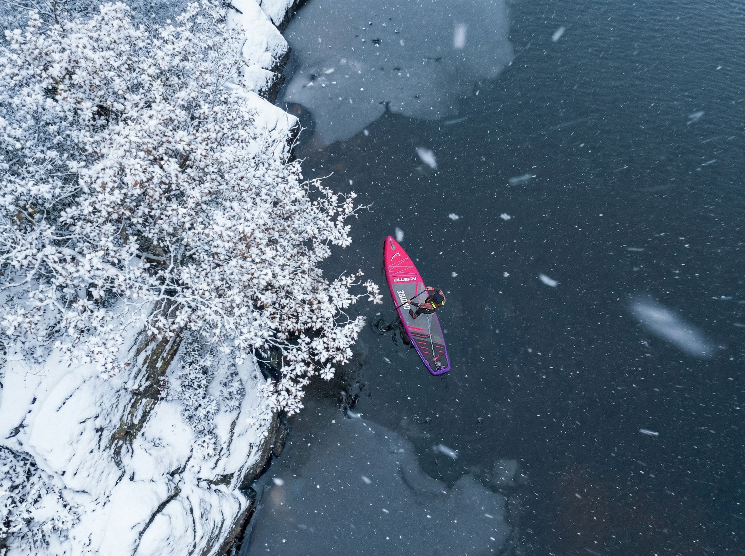 woman paddleboarding on a winter lake in the snow