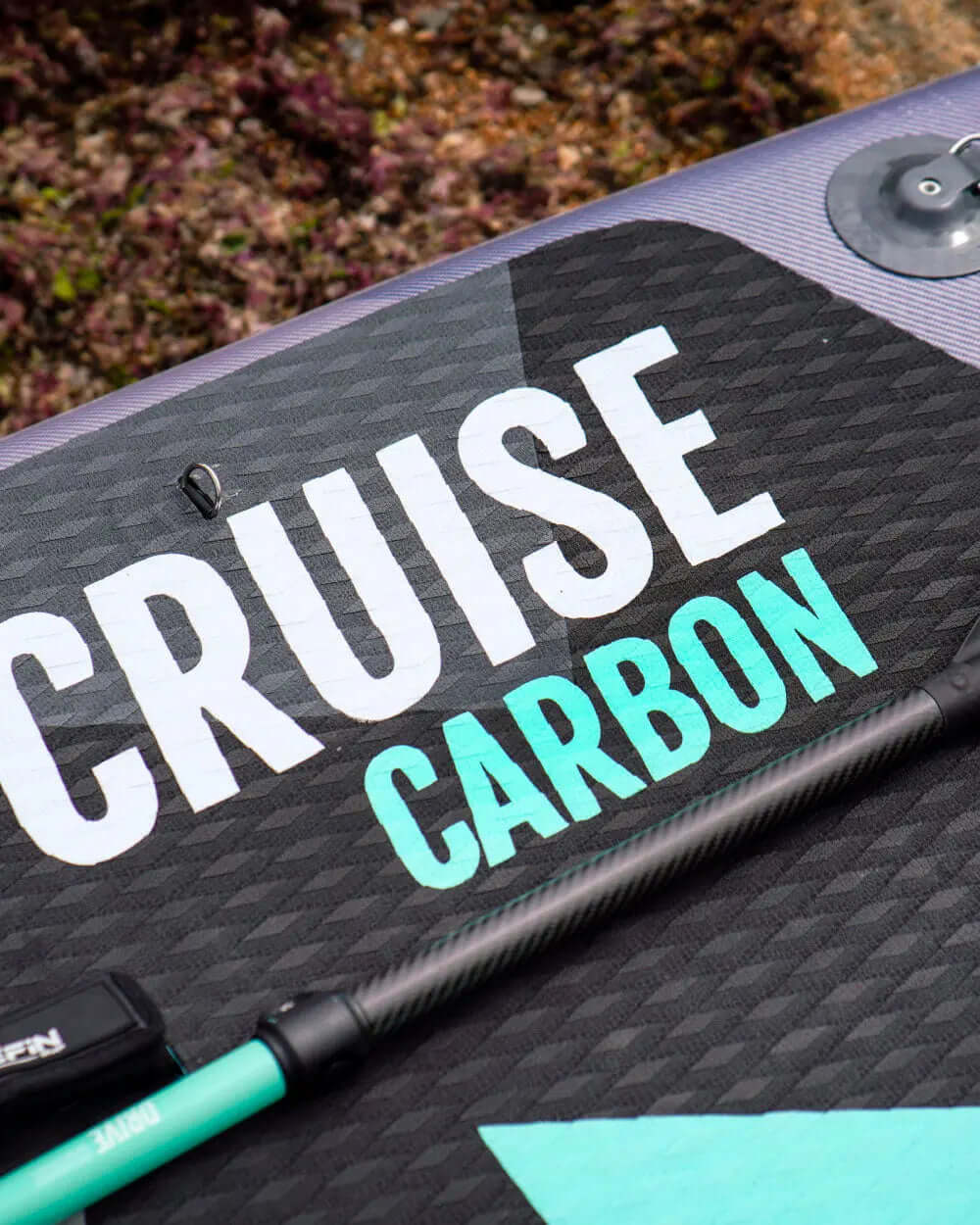 Paddleboard with textured black deck, featuring 'CRUISE CARBON' text and a green paddle