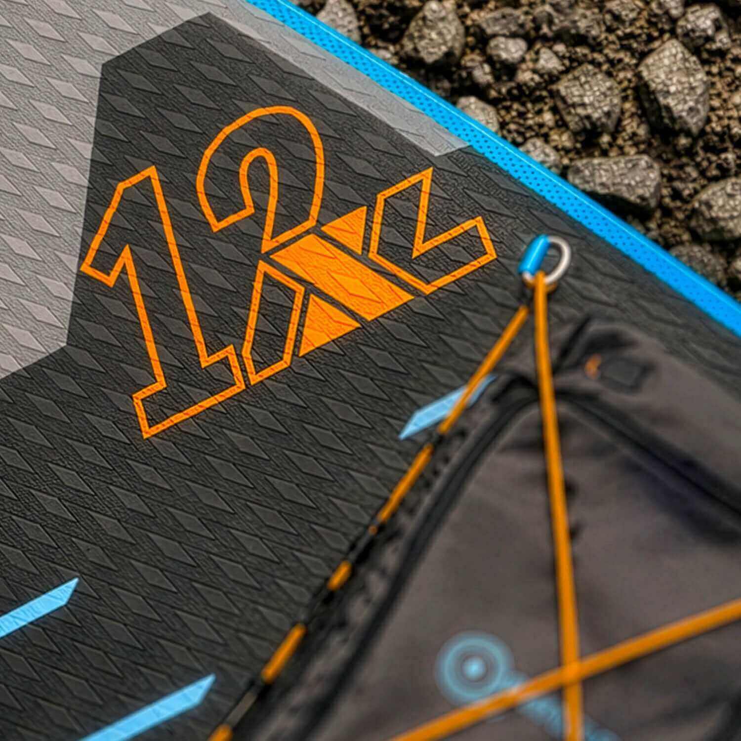 Close-up van een gestructureerd paddleboarddek met het nummer 12 en oranje accenten