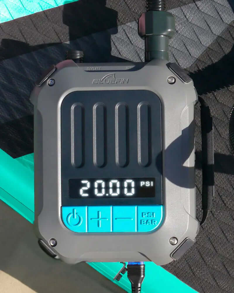 Digitale drukmeter die 20,00 PSI aangeeft, onderdeel van een Bluefin SUP inflatiesysteem op een textuur oppervlak.