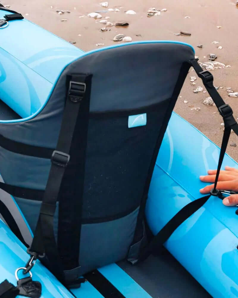 Close-up of a blue inflatable kayak seat with adjustable straps on a sandy beach