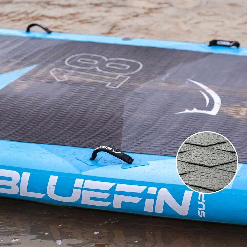 Opblaasbaar paddleboard met textuur op het dek, blauwe randen en middenvin op nat zand