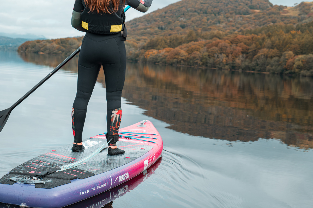 close up shot of a paddleboard on a lake with woman stood on it
