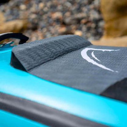 Close-up van een getextureerd grijs dekpad op een blauwe opblaasbare paddleboard met een logo.